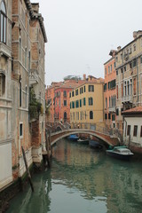 Fototapeta na wymiar Canal in Venice with arching bridge and reflection