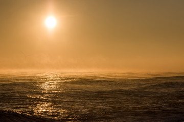 Seascape sunrise. Beautiful misty morning sun over sea with background wind turbine.