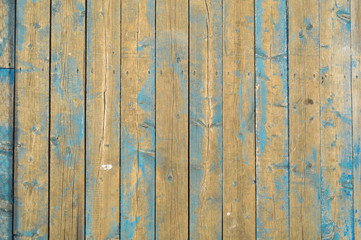 The texture of natural wooden planks with seams painted with blue peeling paint of old shabby scratched cracked ancient. The background