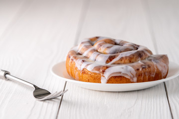 Large gourmet frosted cinnamon roll on white farmhouse table