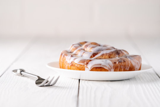 Large Gourmet Frosted Cinnamon Roll On White Farmhouse Table