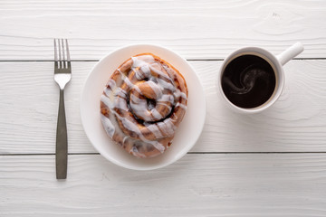 Large gourmet frosted cinnamon roll on white farmhouse table