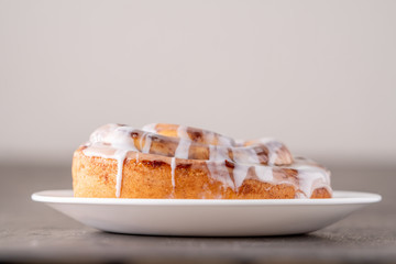 Large gourmet frosted cinnamon roll on brown distressed table.