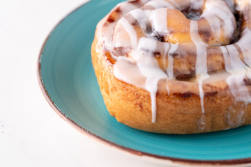 Large gourmet frosted cinnamon roll on marble table.