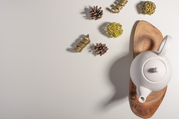 White porcelain teapot with accessories on a wooden board on a white table. View from above. Copy space