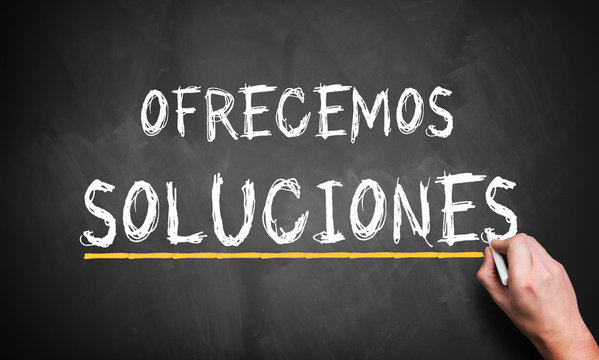 "We Offer Solutions" in Spanish concept from analyst, consultancy or advisor with a businessman writing the words in chalk on a blackboard conceptual of problem solving 