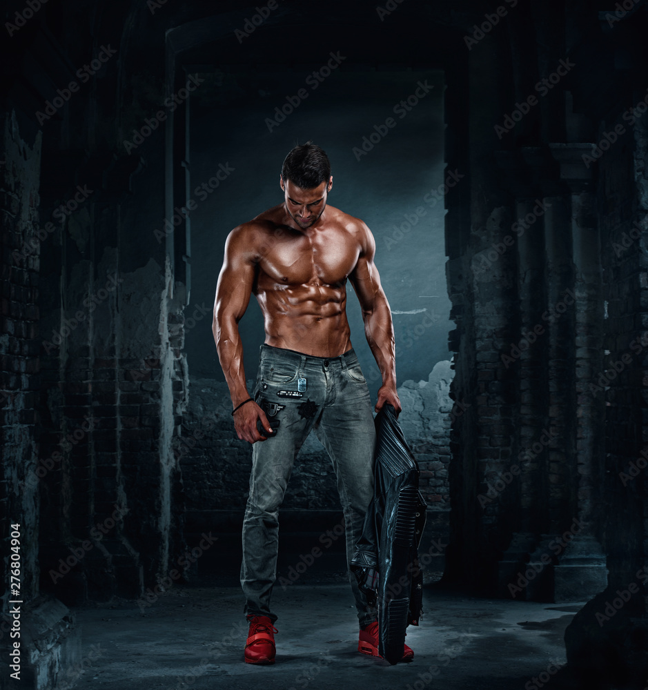 Wall mural handsome athletic male fashion model in leather jacket and jeans