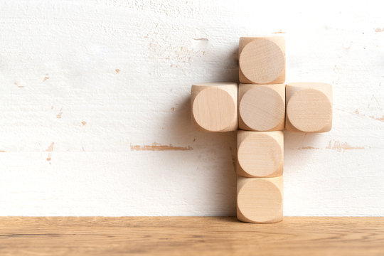 wooden blocks formed as a cross on a table with copy space on a wall