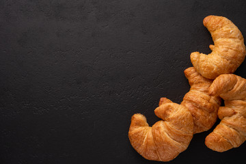 Warm crispy flaky croissant roll on white plate and distressed table.