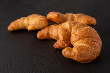 Warm crispy flaky croissant roll on white plate and distressed table.