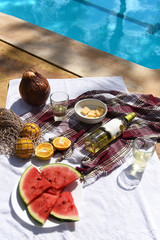 Picnic on the pool with wine, cheese, watermelon, delicious oranges
