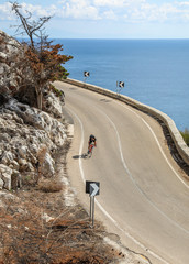 A cyclist coming around the corner on a coastal road in Puglia, Italy. 