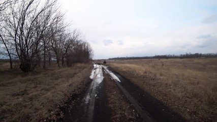 A company of friends is extremely kicking on quad bikes on a country road in the autumn forest, on a muddy wet road