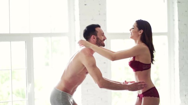 The smiling man and woman in underwear whirling in the room. slow motion