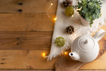 Tea time and tea drinking. White porcelain teapot on a wooden board on a wooden table with a pink garland. View from above. Copy space