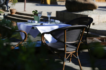 Restaurant terrace with dressed table in the sun and flower reflection