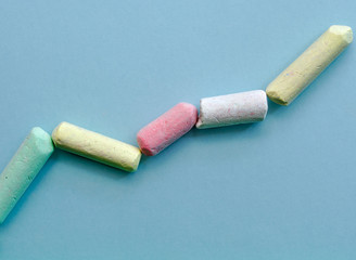 Chalk pieces isolated on light blue background, uptrend line graph made with chalk pieces.