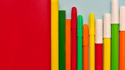 Red surface and colorful markers with copy space, panorama image, back to school concept.
