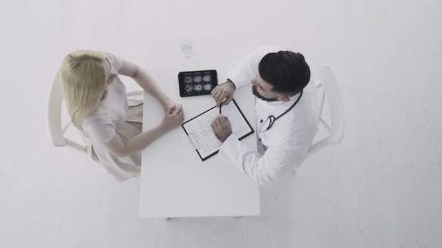 Doctor consults young female patient. Top view 4K