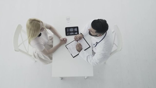 Doctor consults young female patient. Top view 4K