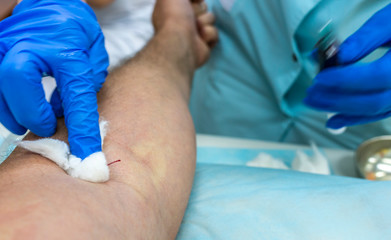 hands of a medical worker in blue gloves take blood from a vein for tests