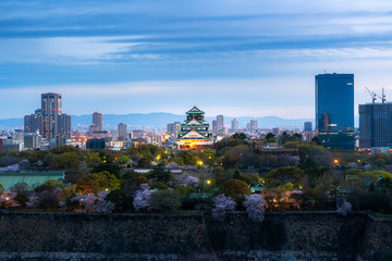 Obraz premium Osaka castle with cherry blossom and business district in background at Osaka, Japan.