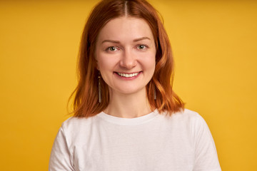 Photo closeup of optimistic woman 20s with curly ginger hair smiling at camera isolated over yellow background