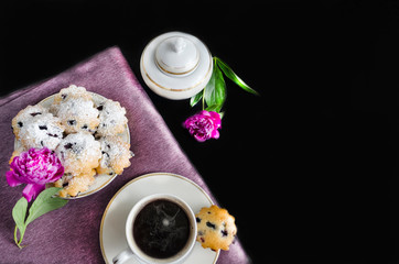 morning coffee with a cupcake and flowers. women things. good morning! blueberry muffins and americano on a purple and black background. Espresso with baking. pink peonies in a stylish decor.