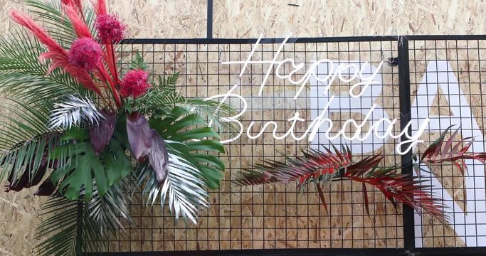 Decoration For Birthday Party. Photo Zone With Painted Plants And Flowers And Neon Inscription With A Wish For A Happy Birthday