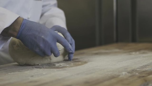 Chef kneading dough in flour on a table