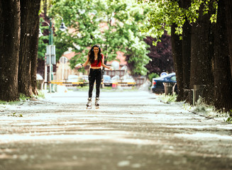 Fitness woman roller skating while listening music on headphones