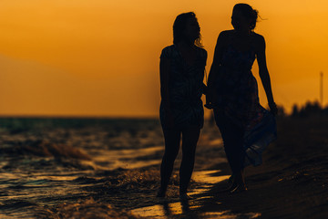 Girls walking on the wet sandy beach during sunset