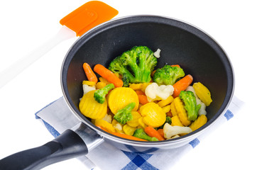 Frying pan with mix of frozen vegetables, isolated on white background.