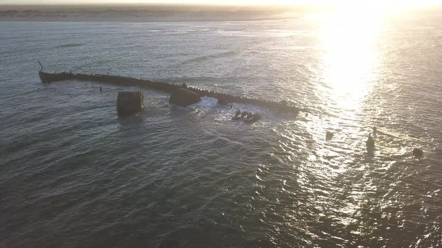 Drone flies over a rusty wreck in the middle of Coral Bay in Western Australia. Aerial view of the Indian Ocean in the beautiful evening light