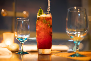Red Juicy Fruit refreshment in high Glass with straw tube with ice and topping decoration for customer, Fresh smoothies Juice from natural to make diet good health for Dinner table with wine glasses