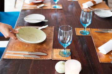 Abstract utensils fork knife spoon glass and leather plate mat which classic look on napkin top of table with blurry restaurant background