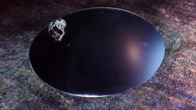 Mirror on a grunge table with a skull necklace in the reflection.