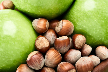Brown hazelnuts and vibrant green of fresh Granny Smith apples close-up.