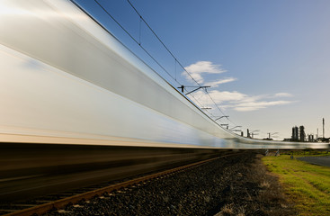 A blurred time lapse of a train traveling across the frame on a curve.