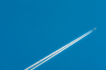 Airplane with white condensation tracks. Jet plane on clear blue sky with vapor trail. Travel by...