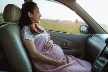 asian pregnant woman enjoy the car trip while sitting on passanger seat