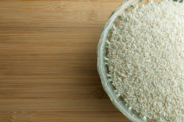 Raw rice in a bowl on a wooden cutting board