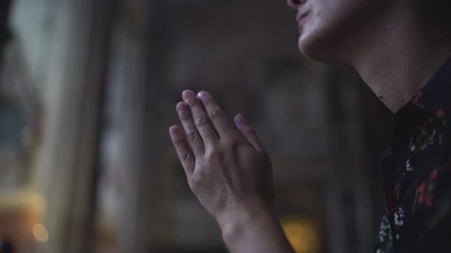 Woman praying in church. Close up, UHD 4K