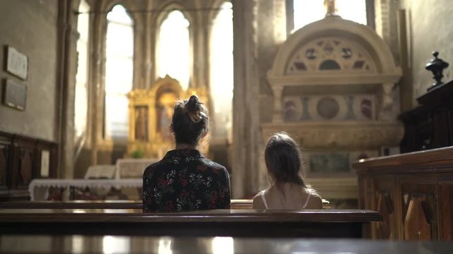 Mother and Daughter is Praying in Catholic Church