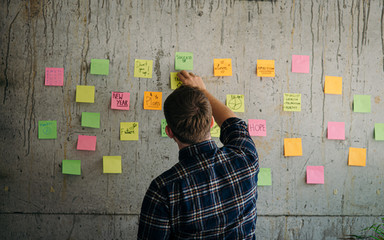 Man holding sticky paper message write target with cement wall.