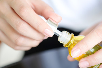 hands of a beautiful woman Dropping serum collagen moisturizer of face into clear yellow bottle soft light background. Protector skin Treatment facial essence oil, Vitamin C. Beauty and spa Con