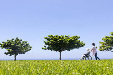 車いすで散歩するシニアと介護ヘルパー