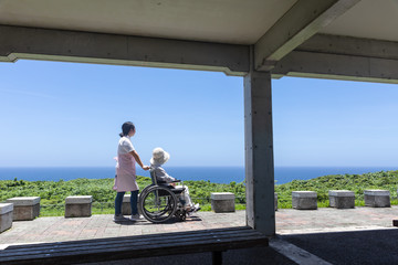 車いすで散歩するシニアと介護ヘルパー