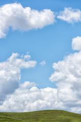 Green hills with cloudy blue sky.