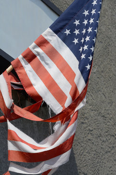 American Flag On Flag Pole Torn And Divided Stripes By Strong Winds